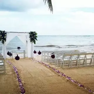 Beachfront wedding ceremony setup with white arch and petal aisle at Catalonia Royal Tulum
