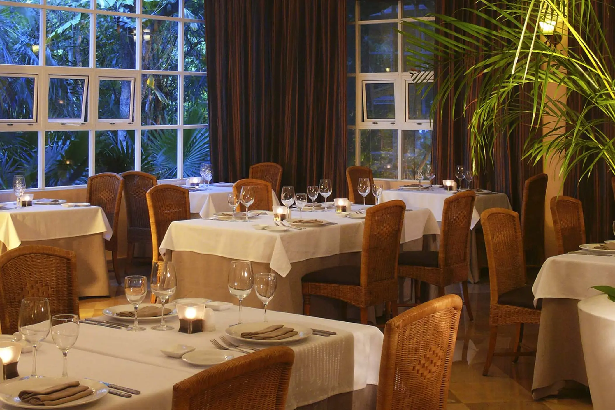 La Toscana restaurant dining room with white tablecloths and wicker chairs at Catalonia Royal Tulum, Tulum