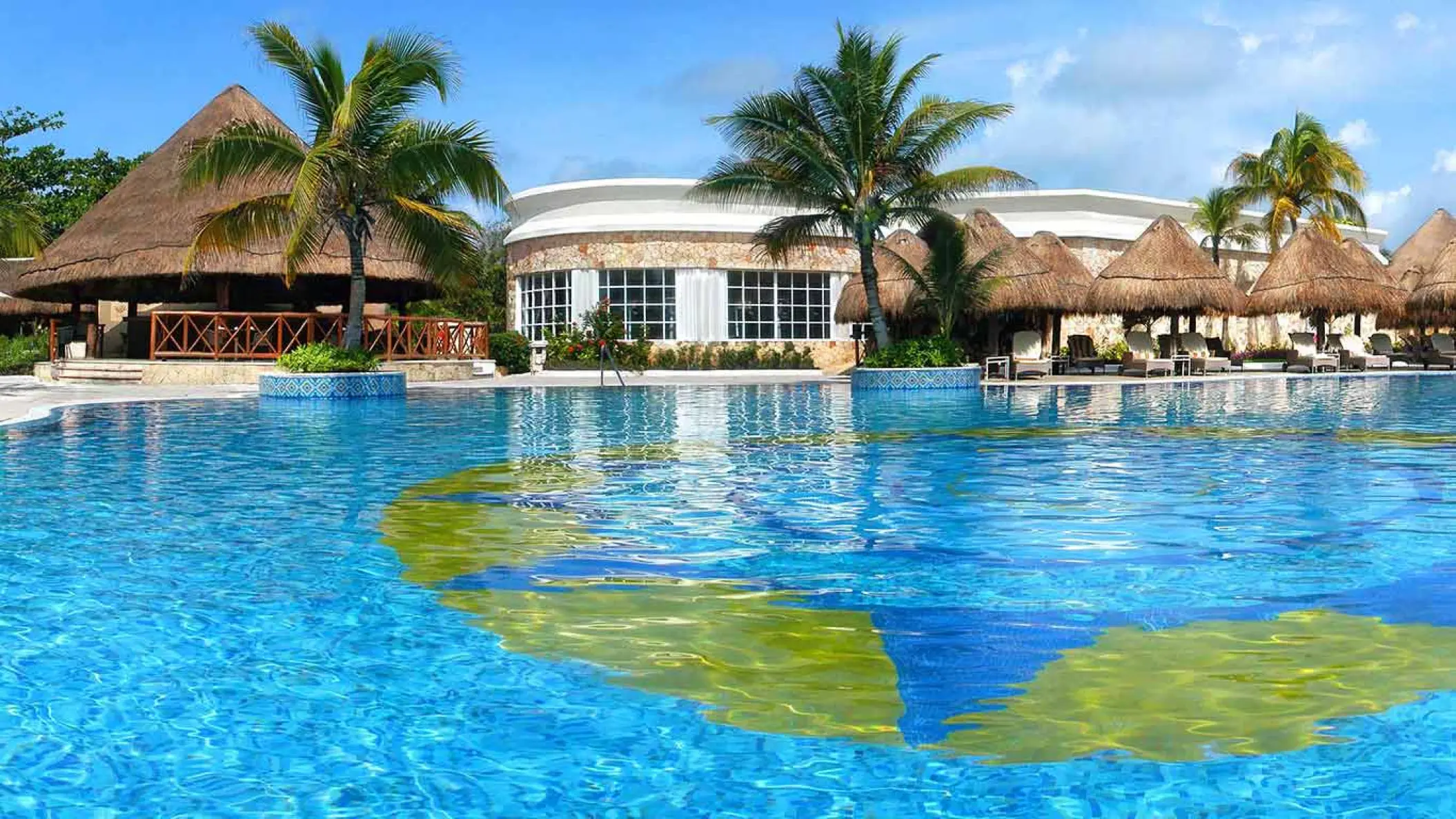 Catalonia Royal Tulum large outdoor swimming pool with palapas and tropical palms, Tulum