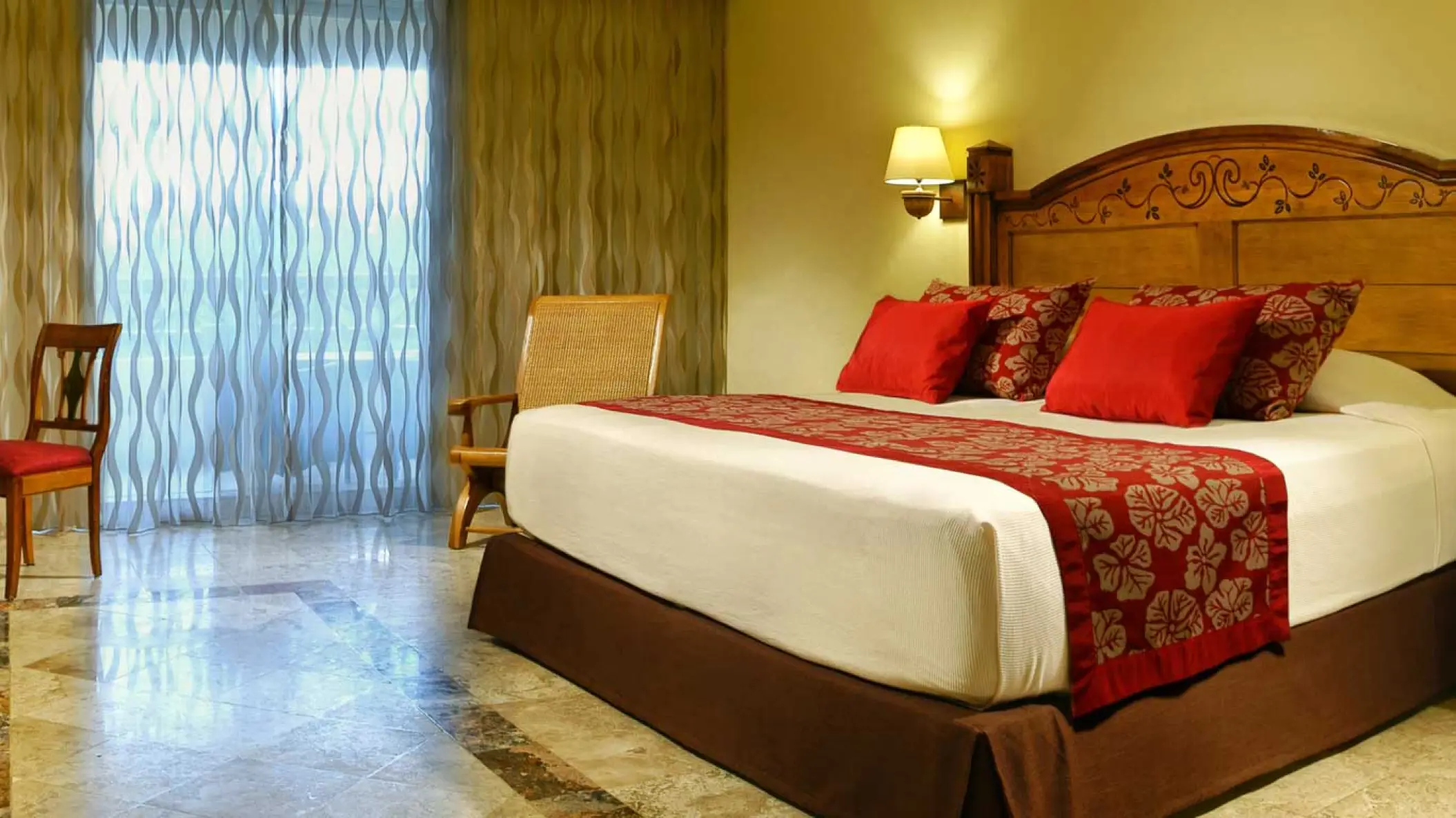Guest suite with red accents and carved wooden headboard at Catalonia Royal Tulum