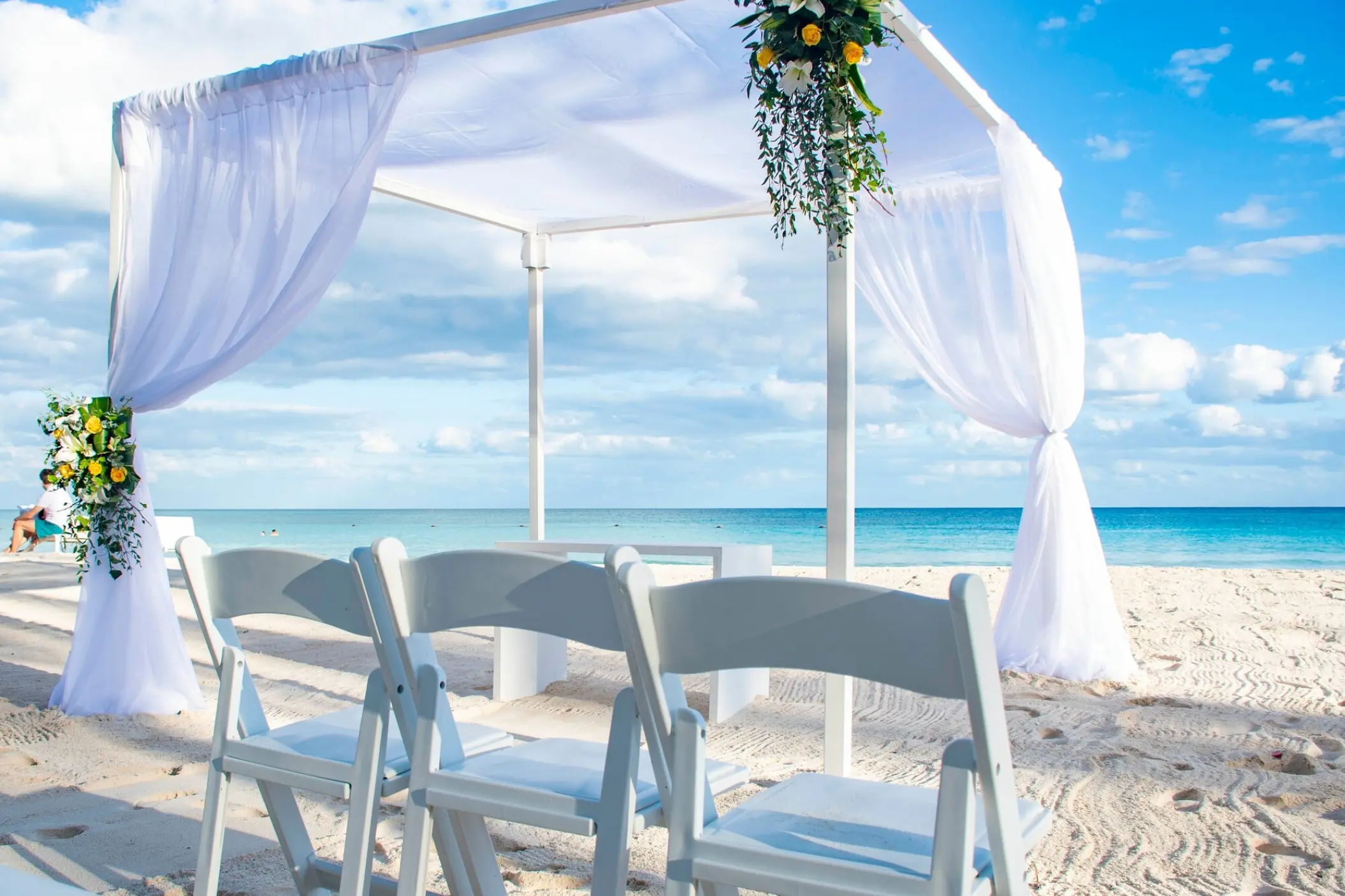 Beachfront wedding ceremony with a white draped gazebo and folding chairs at Catalonia Royal Tulum, Tulum