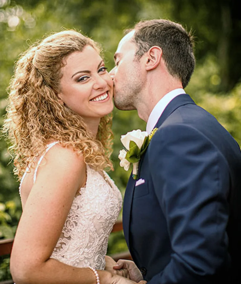Bride smiles when groom kisses her chick
