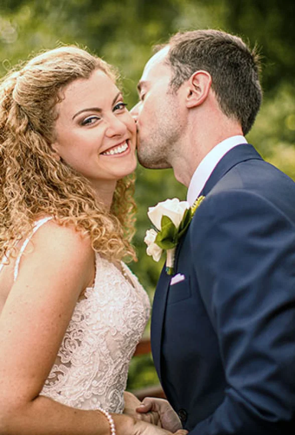 Bride smiles when groom kisses her chick