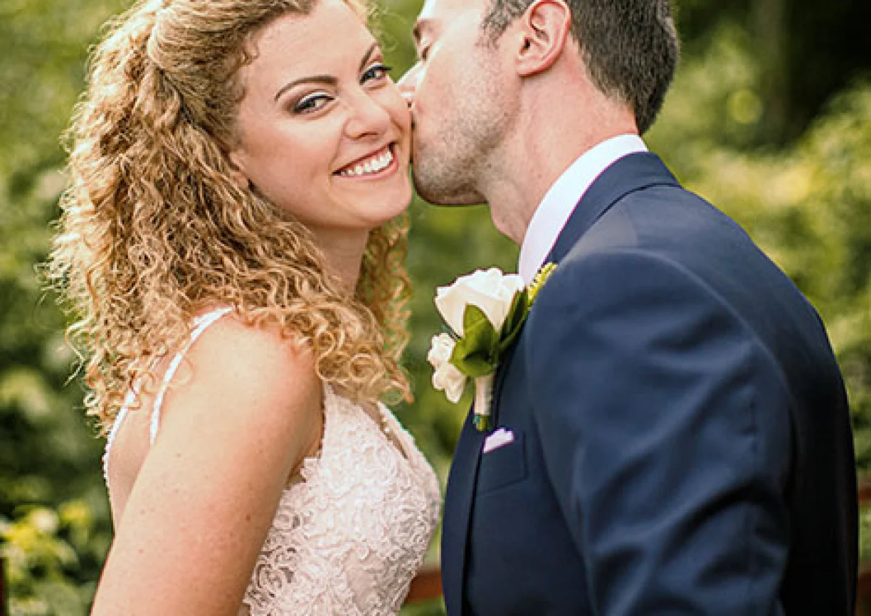 Bride smiles when groom kisses her chick