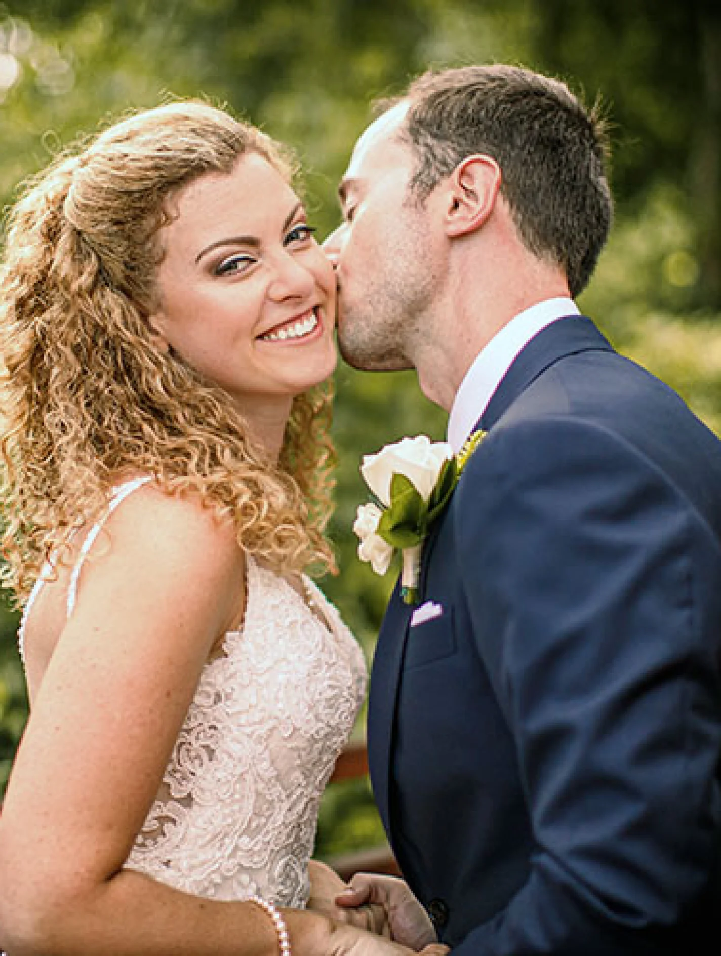 Bride smiles when groom kisses her chick