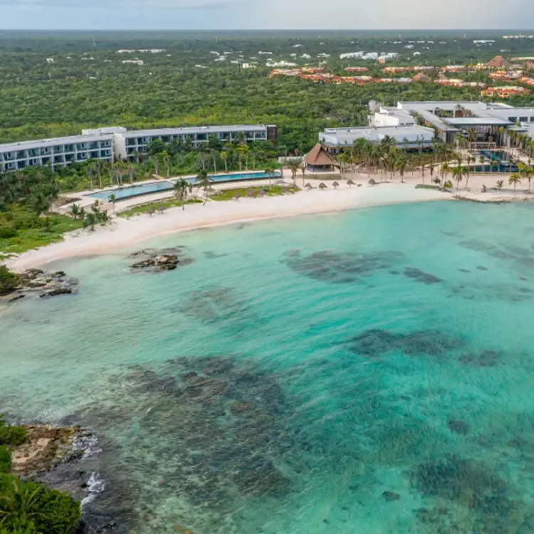 Aerial view of Conrad Tulum beachfront buildings and private turquoise bay, Tulum