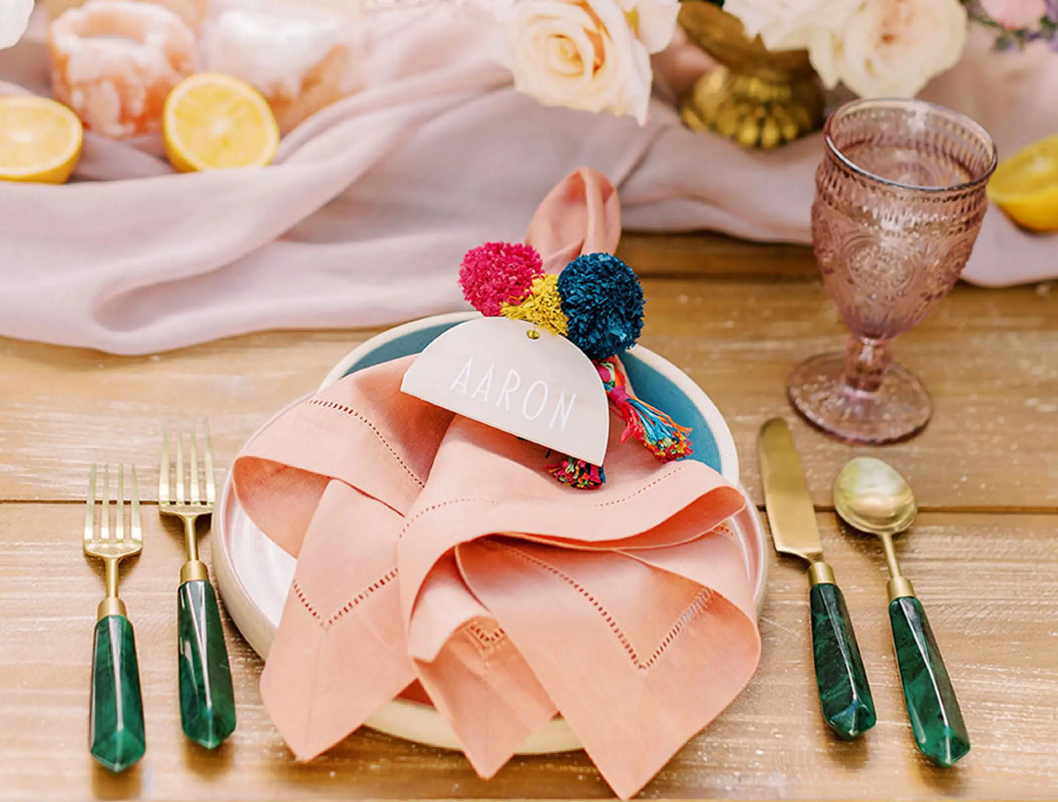 Colorful wedding place setting with pink napkin and pom-poms at Conrad Tulum, Tulum