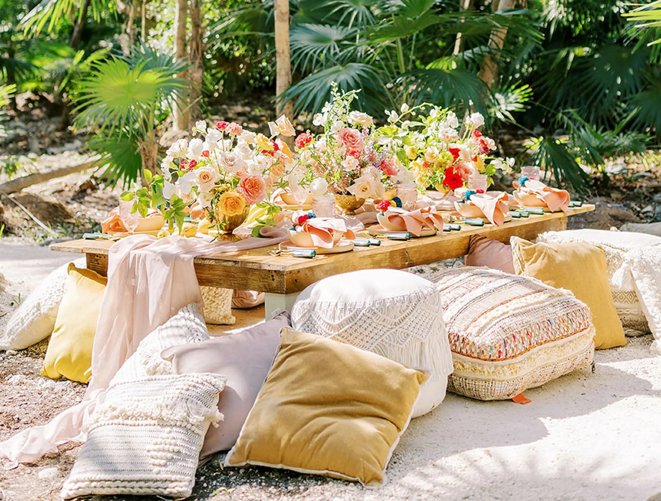 Boho wedding reception floor seating with cushions and floral centerpieces at Conrad Tulum, Tulum