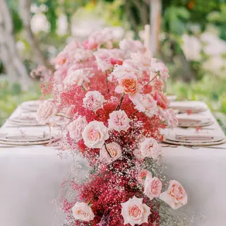 Pink and red floral centerpiece on a wedding reception table at Conrad Tulum, Tulum