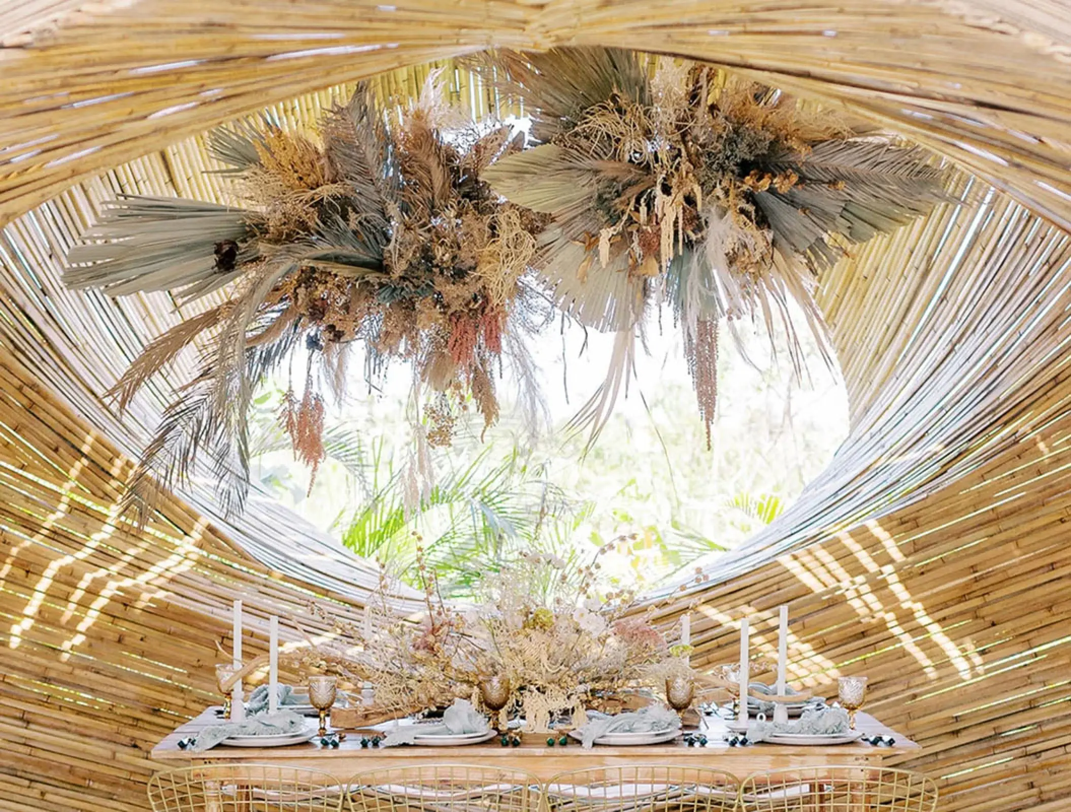 Wedding reception table under a bamboo structure with dried floral arrangements at Conrad Tulum, Tulum