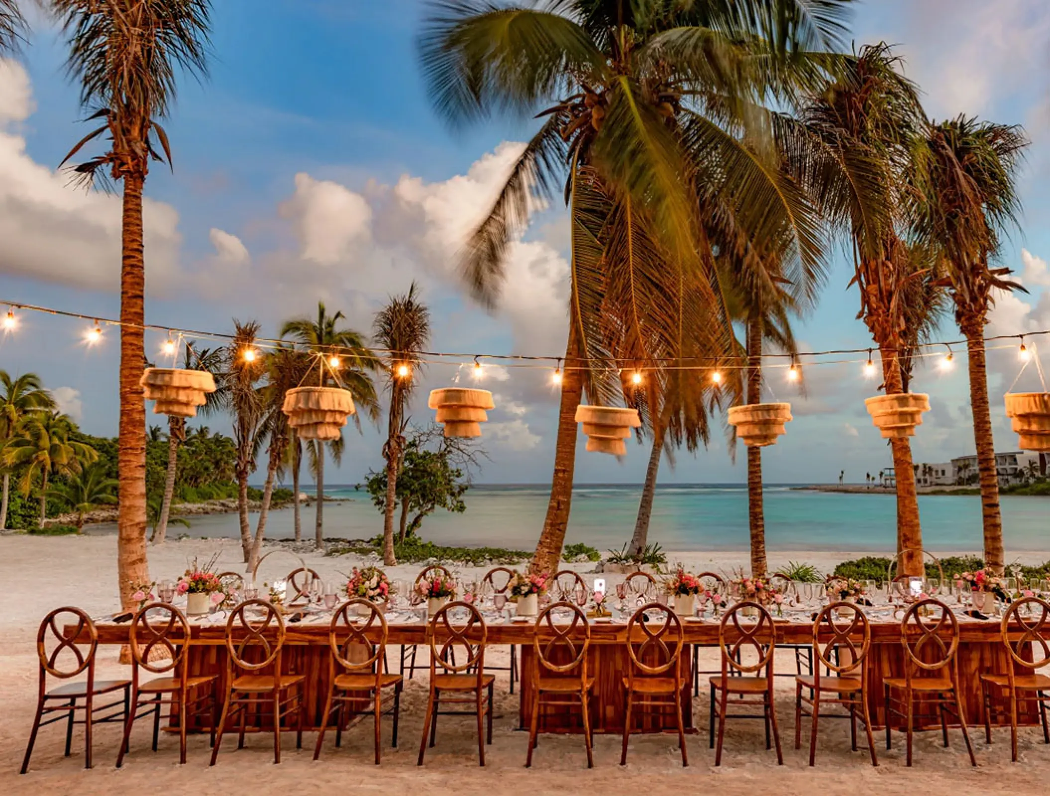 Long table beach reception with hanging lanterns and string lights at Conrad Tulum, Tulum