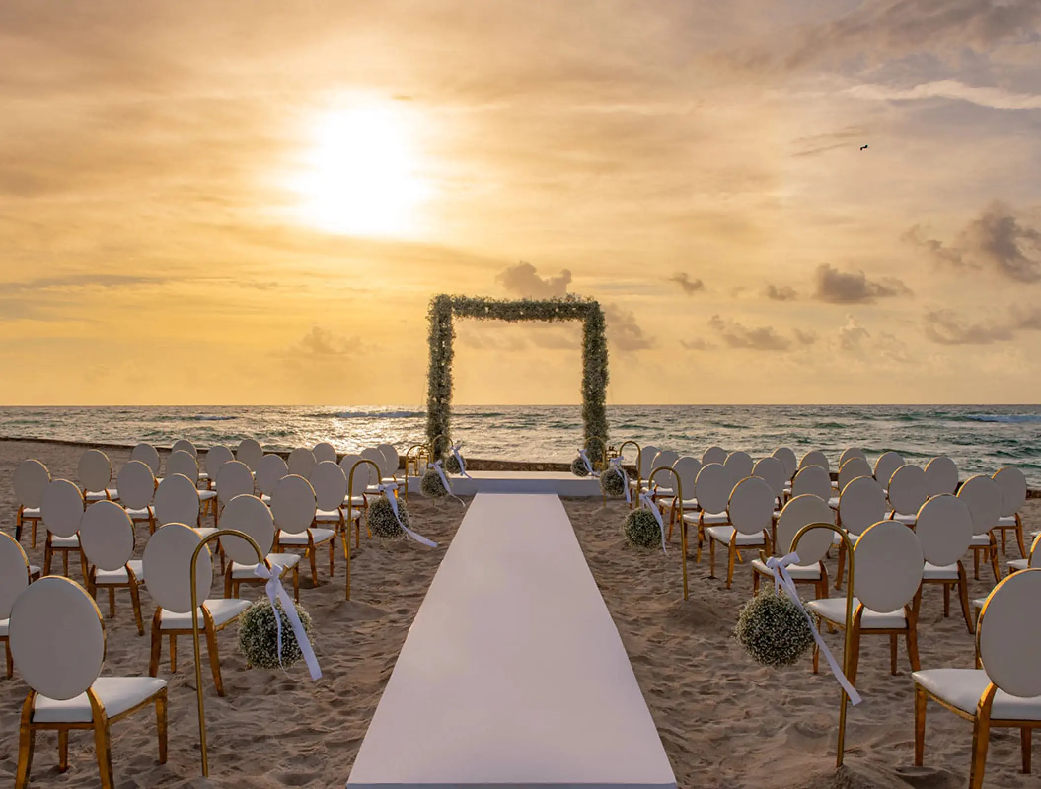 Beachfront wedding ceremony setup at sunset at Hilton Tulum, Tulum