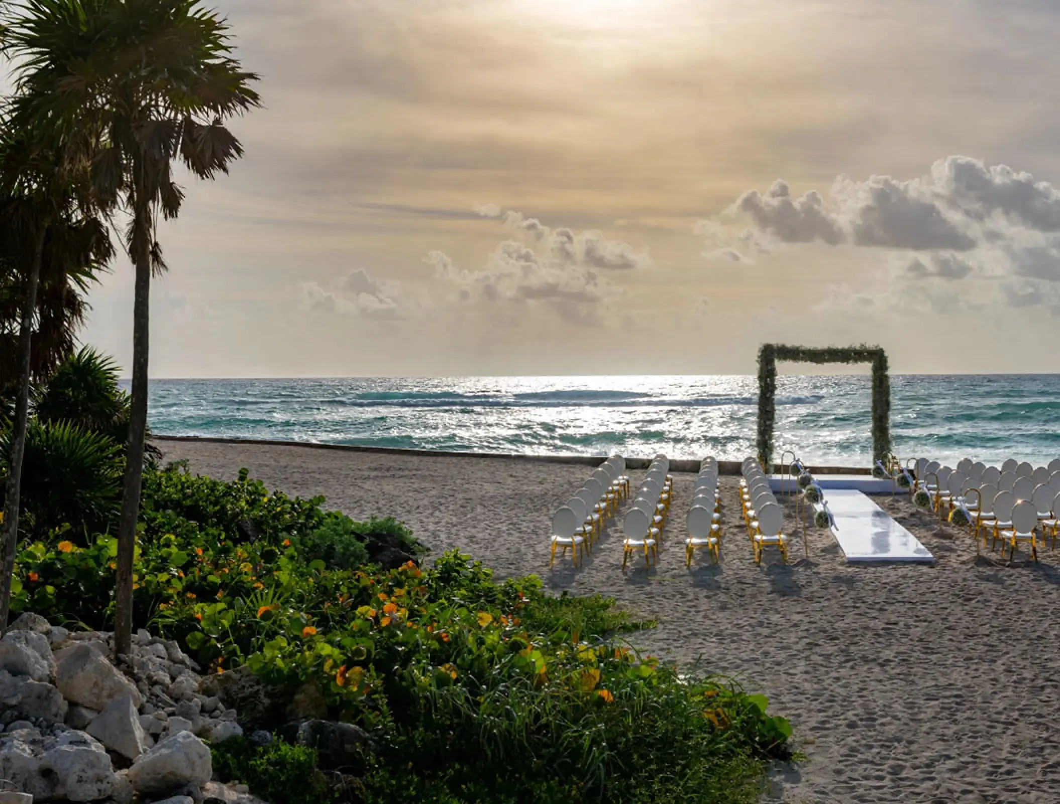 Beachfront wedding ceremony with floral arch and white aisle at Conrad Tulum, Tulum