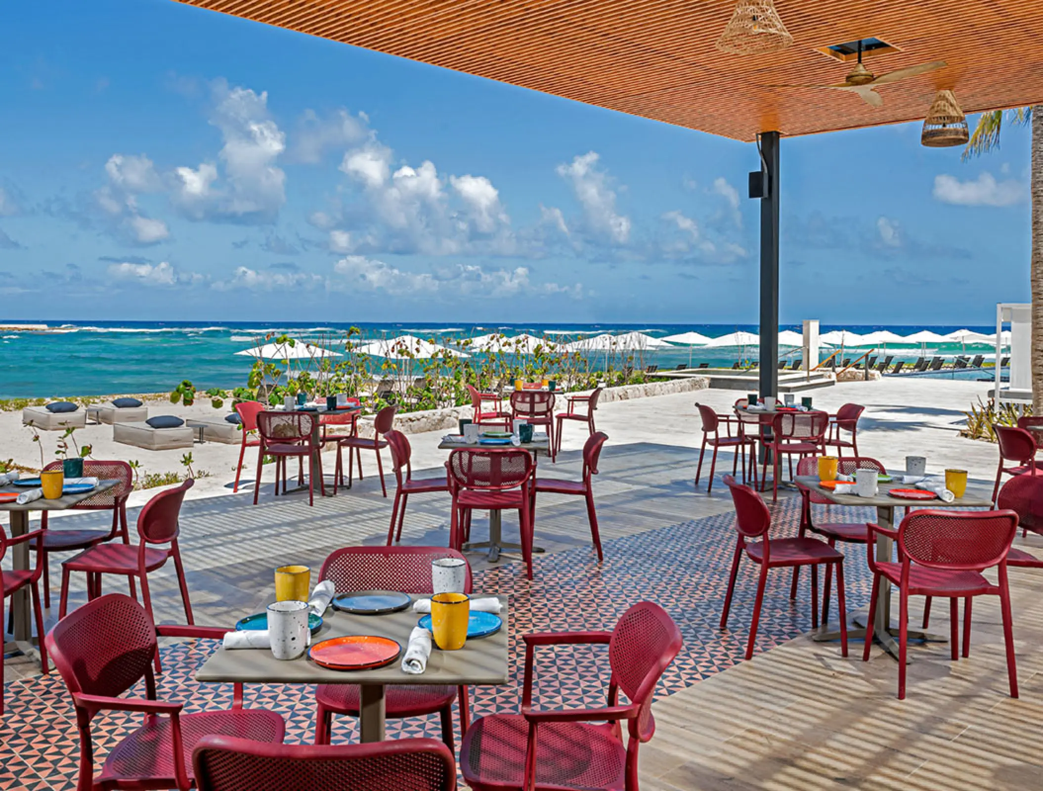 Oceanview restaurant terrace with red chairs at Conrad Tulum, Tulum