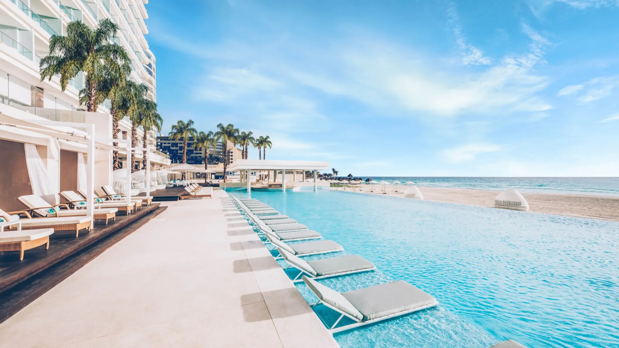 Beachfront infinity pool with in-water lounge chairs at Coral Level at Iberostar Selection Cancun
