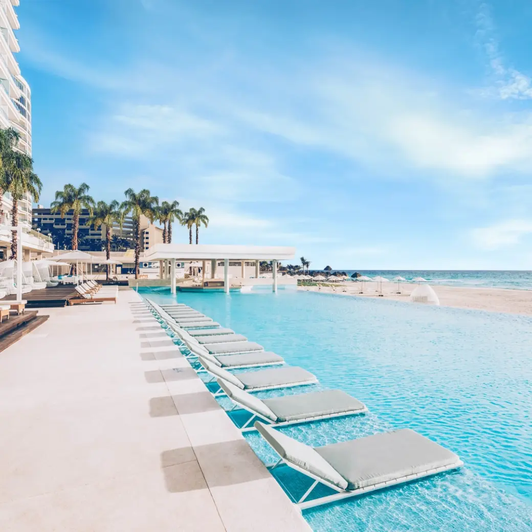 Beachfront infinity pool with in-water lounge chairs at Coral Level at Iberostar Selection Cancun