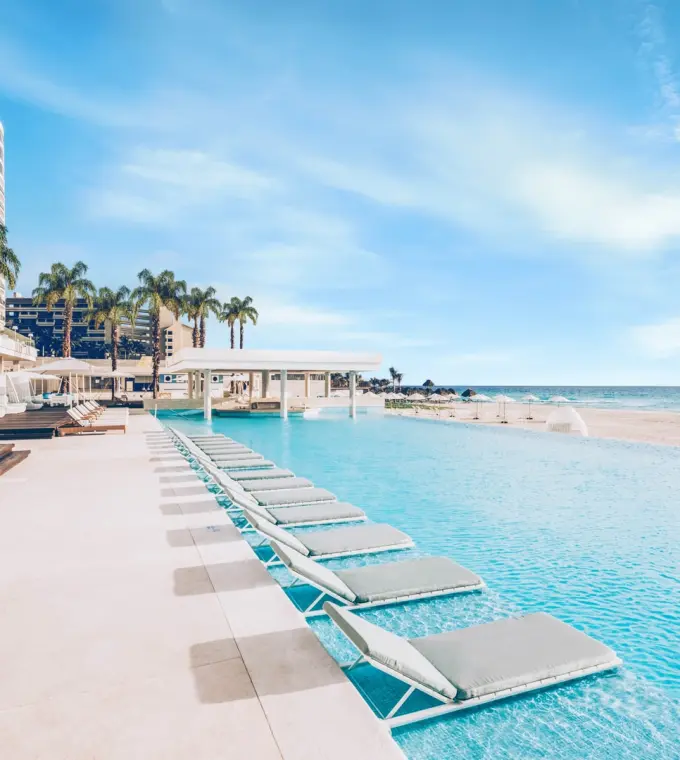 Beachfront infinity pool with in-water lounge chairs at Coral Level at Iberostar Selection Cancun
