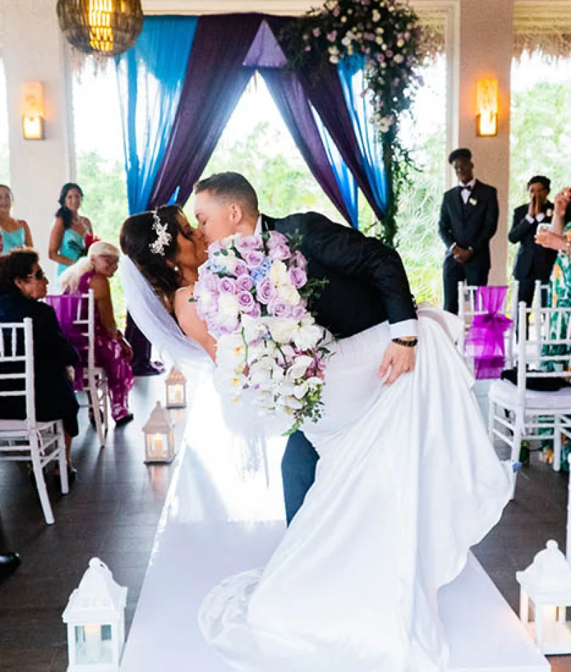 newlyweds kisses on front of the isle