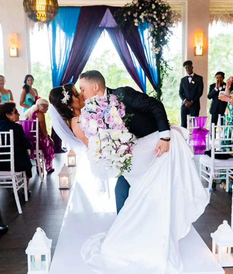 Crystal & Chelsea's first kiss during their indoor wedding ceremony