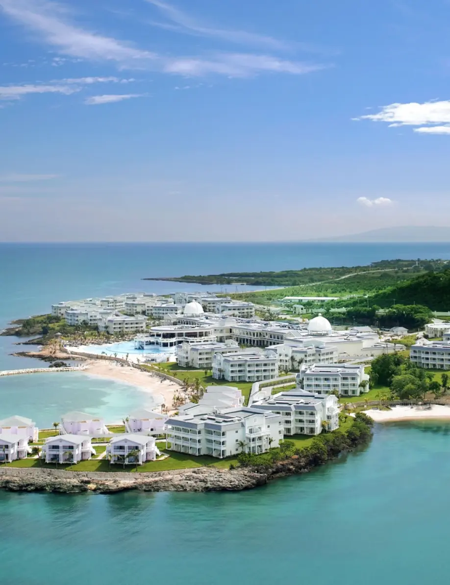 Aerial view of a coastal resort on a peninsula with white buildings and turquoise water in Lucea, Jamaica