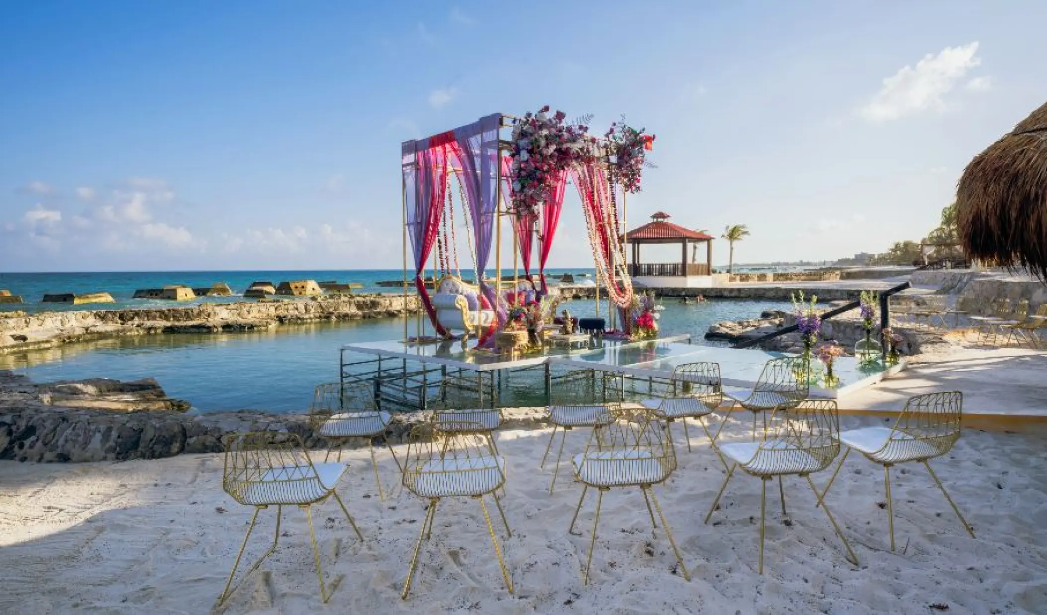 Beachfront wedding ceremony setup with pink drapes at El Dorado Casitas Royale, Riviera Maya