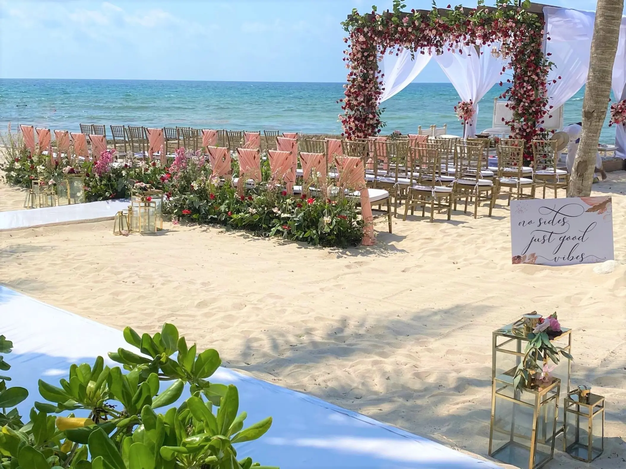 Beachfront wedding ceremony with a floral gazebo and pink chair sashes at El Dorado Casitas Royale, Riviera Maya