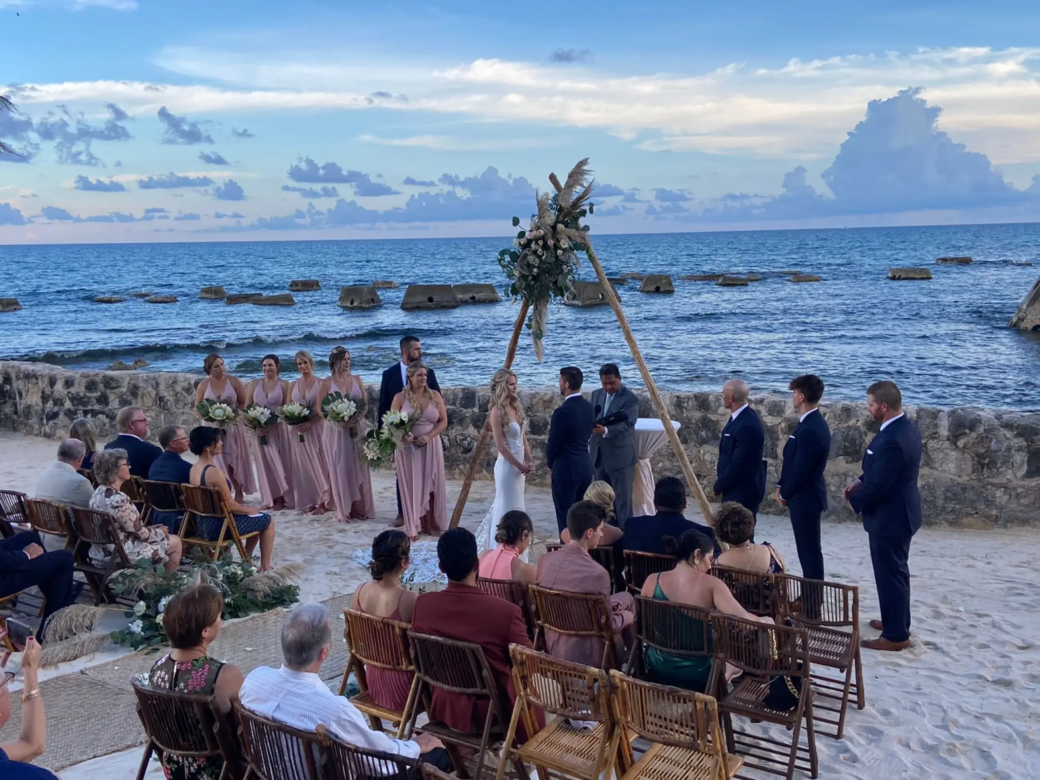 Beachfront wedding ceremony under a floral tepee arch at El Dorado Casitas Royale, Riviera Maya