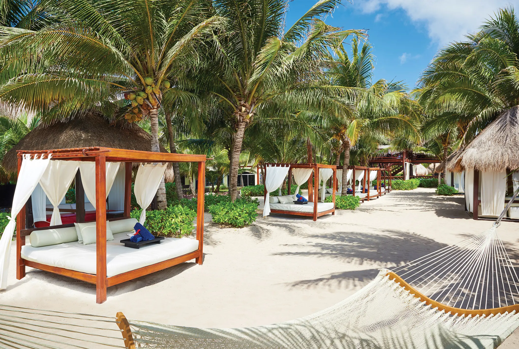 Beach cabanas and hammocks under palm trees at El Dorado Royale, Riviera Maya