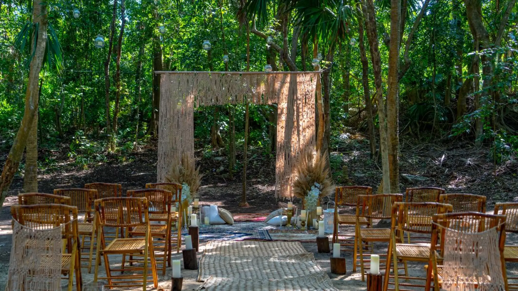 Jungle wedding ceremony setup with a rustic wooden arch and chairs at El Dorado Royale, Riviera Maya