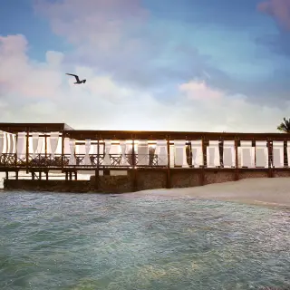Wooden beachfront dining deck with white curtains at El Dorado Royale, Riviera Maya