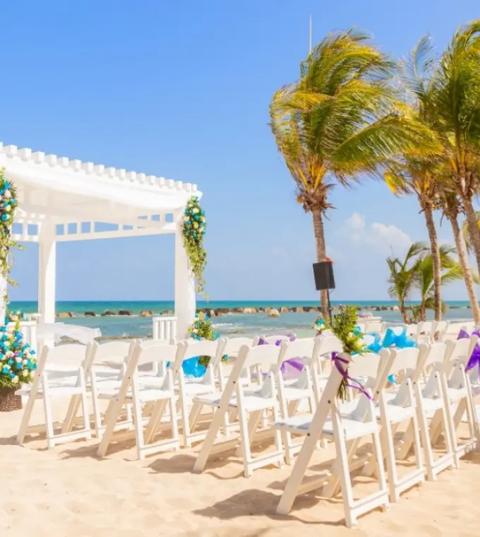 Beachfront wedding ceremony with white pergola and blue flower arrangements at El Dorado Royale, Riviera Maya