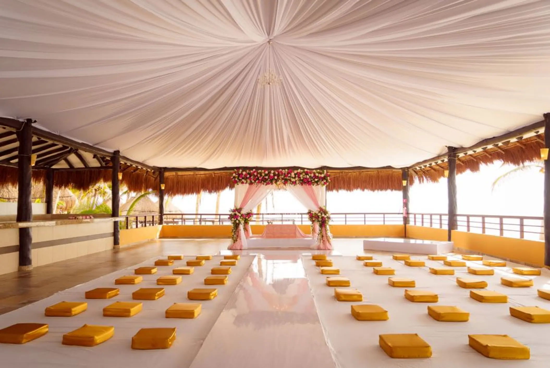 Palapa wedding ceremony setup with draped ceiling and cushion seating at El Dorado Seaside Palms, Riviera Maya