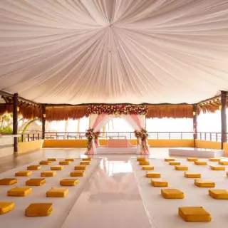 Palapa wedding ceremony setup with draped ceiling and cushion seating at El Dorado Seaside Palms, Riviera Maya
