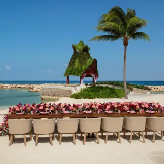 Beach wedding reception setup with floral runner and beige chairs at Dreams Aventuras, Riviera Maya