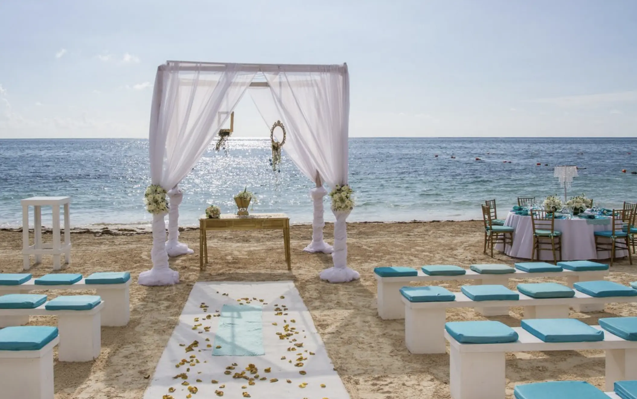 Beachfront wedding ceremony with white gazebo and teal cushions at Dreams Aventuras, Riviera Maya