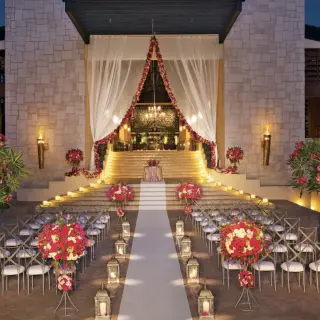 Evening wedding ceremony setup with red floral arrangements at Dreams Aventuras, Riviera Maya