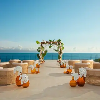 Terrace wedding ceremony with wicker chairs and a floral arch at Dreams Bahia Mita, Puerto Vallarta