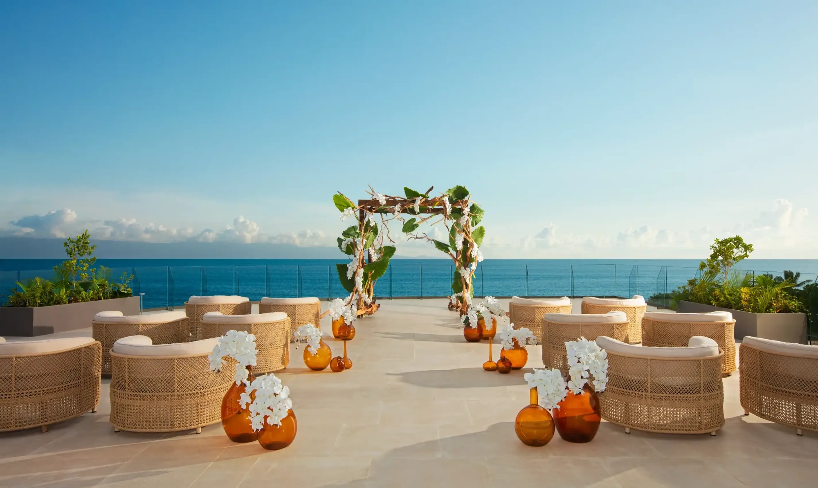 Terrace wedding ceremony with wicker chairs and a floral arch at Dreams Bahia Mita, Puerto Vallarta
