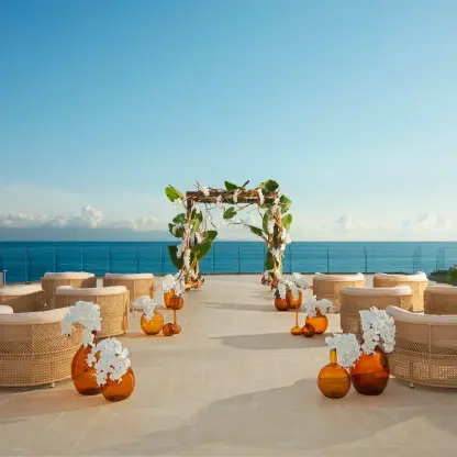 Terrace wedding ceremony with wicker chairs and a floral arch at Dreams Bahia Mita, Puerto Vallarta