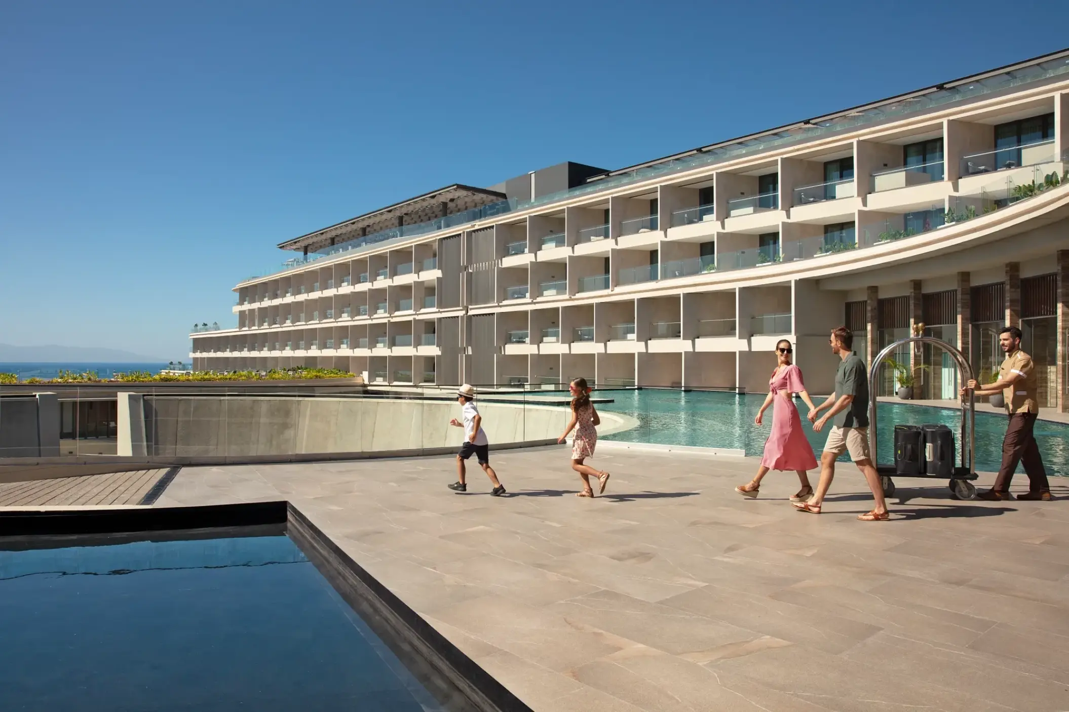 Families walking past the main pool and hotel terrace at Dreams Bahia Mita, Puerto Vallarta