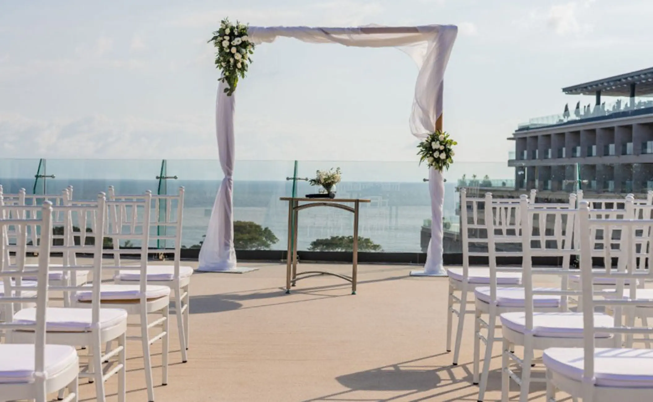 Rooftop wedding ceremony setup with white chairs and floral arch at Secrets Bahia Mita, Puerto Vallarta