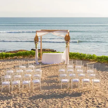 Beachfront wedding ceremony with a wooden arch and white chairs at Dreams Bahia Mita, Puerto Vallarta