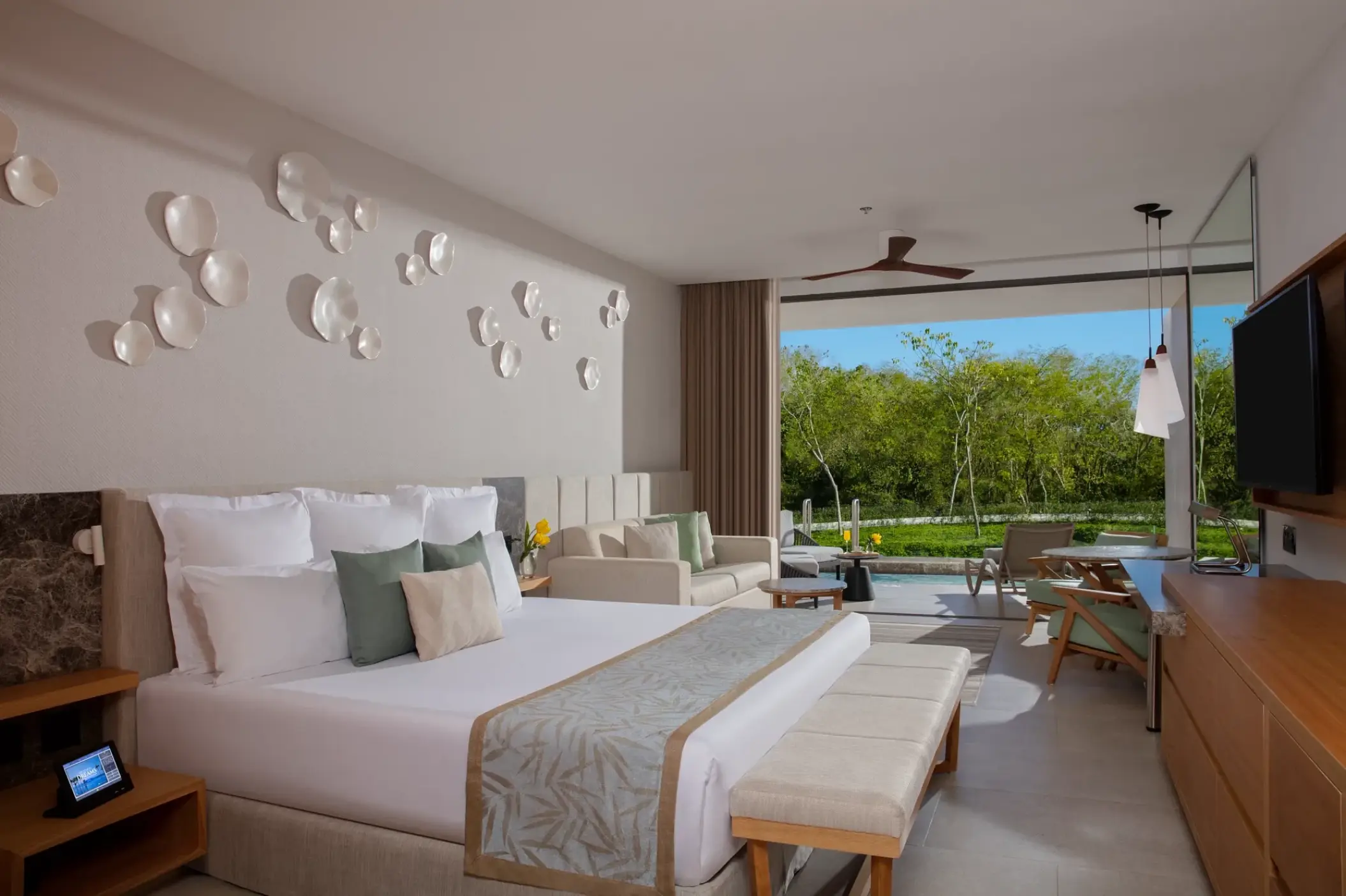 Dreams Bahia Mita suite with a king bed, sitting area, and patio opening to tropical greenery, Puerto Vallarta