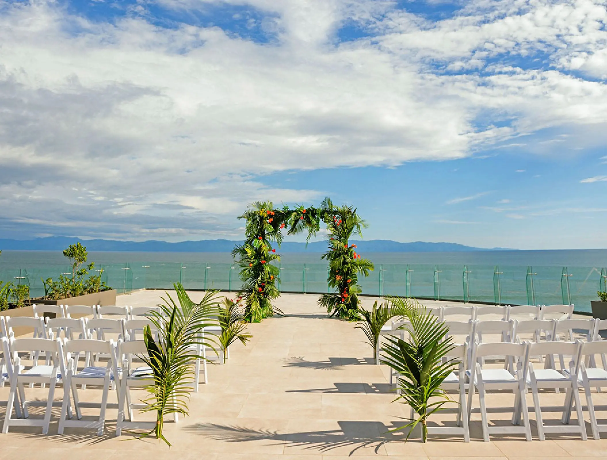 Rooftop wedding ceremony with floral arch and white chairs at Secrets Bahia Mita, Puerto Vallarta