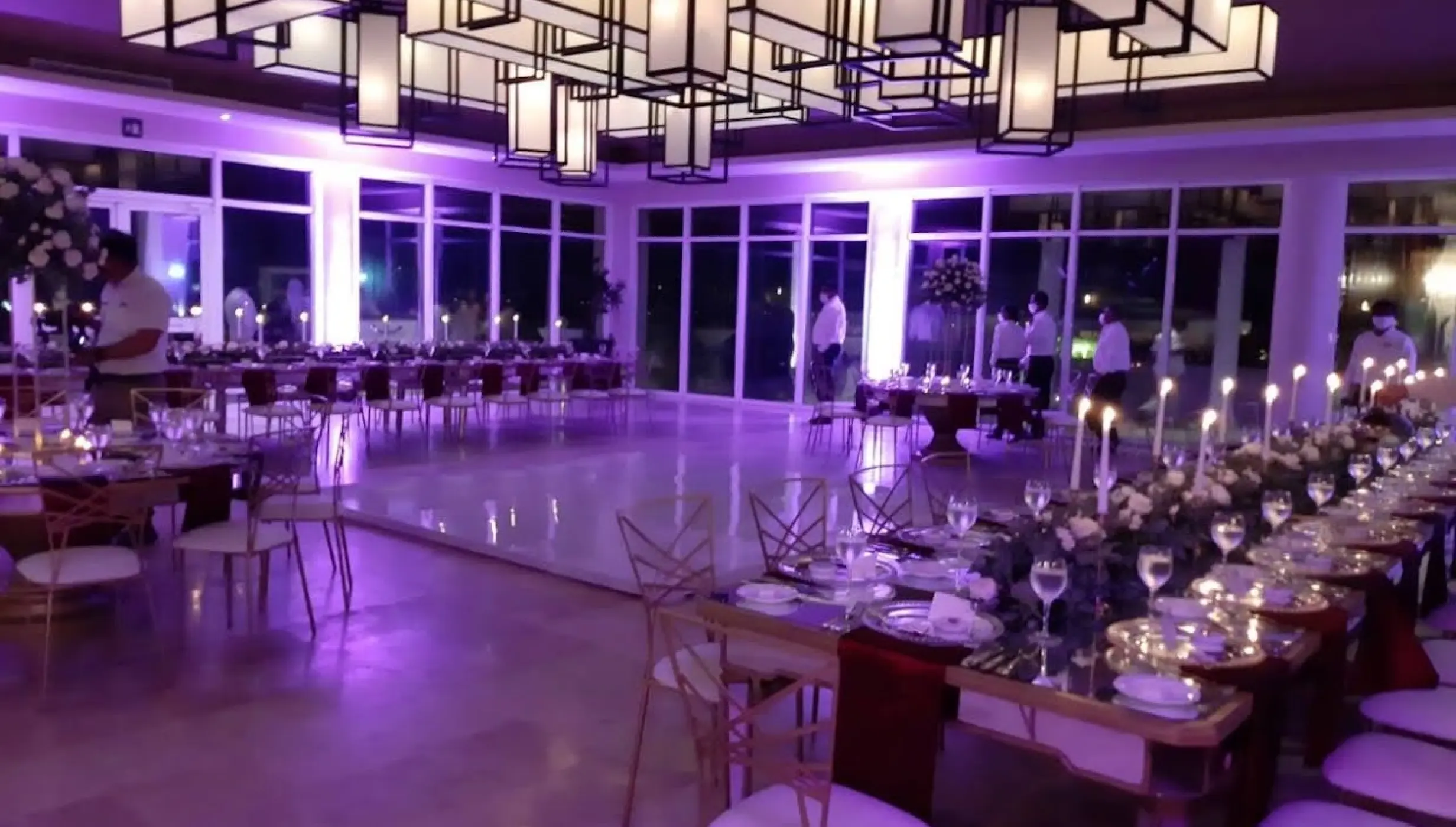 Indoor wedding reception at Dreams Jade, Riviera Maya, featuring purple lighting and long banquet tables
