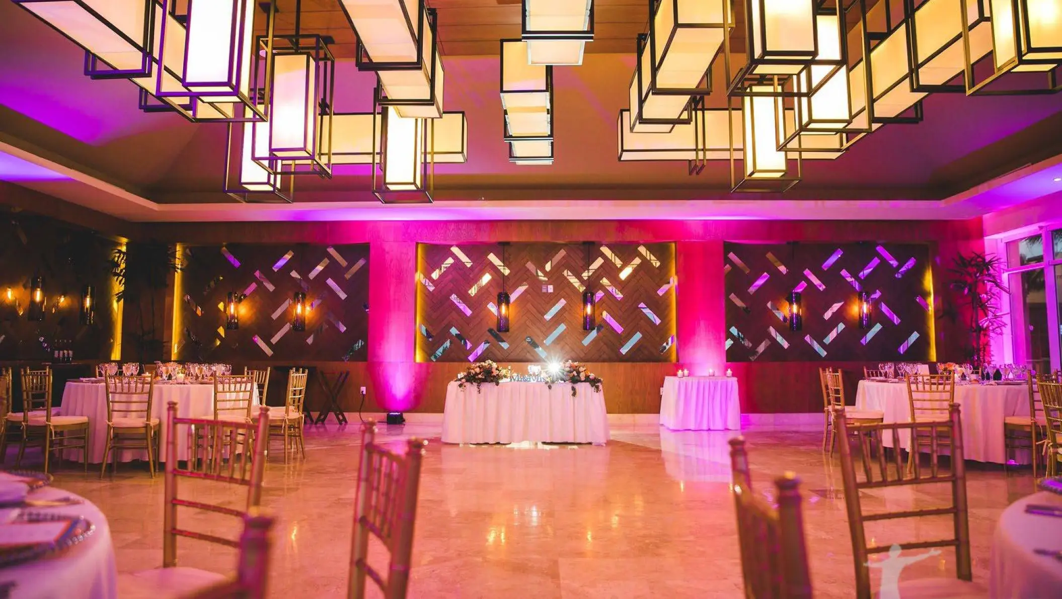 Indoor wedding reception with pink lighting and rectangular lanterns at Dreams Jade, Riviera Maya