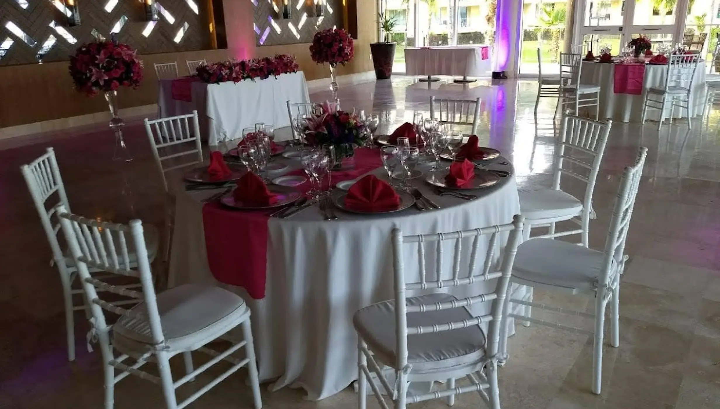 Indoor wedding reception with white chairs and pink floral centerpieces at Dreams Jade, Riviera Maya