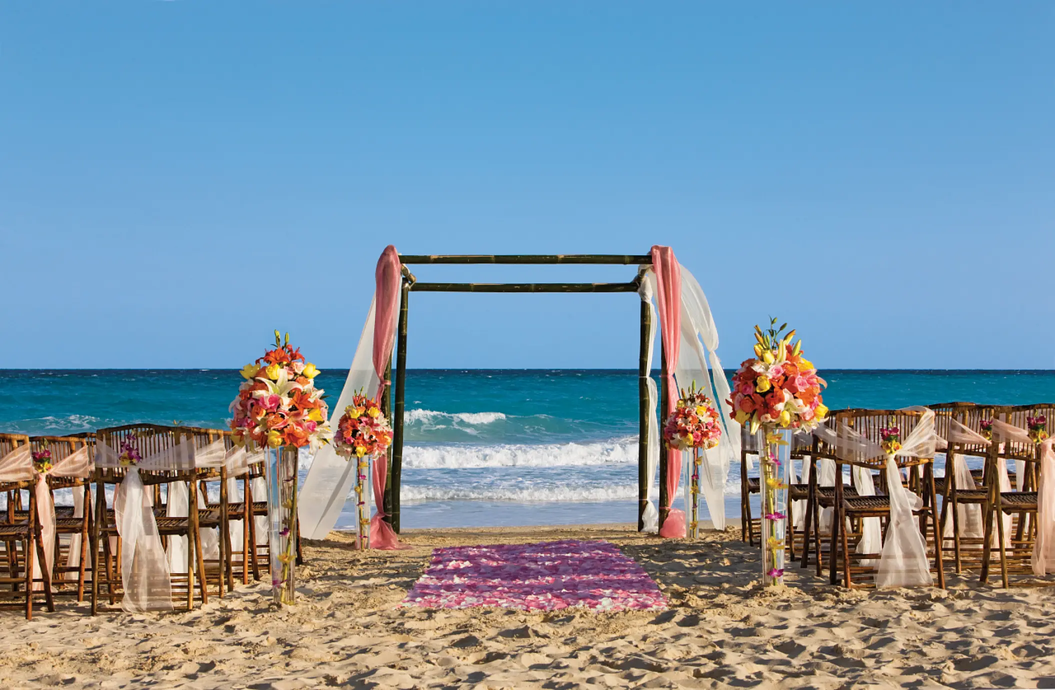 Beachfront wedding ceremony with a floral huppah and ocean views at Dreams Jade, Riviera Maya