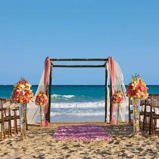 Beachfront wedding ceremony with a floral huppah and ocean views at Dreams Jade, Riviera Maya