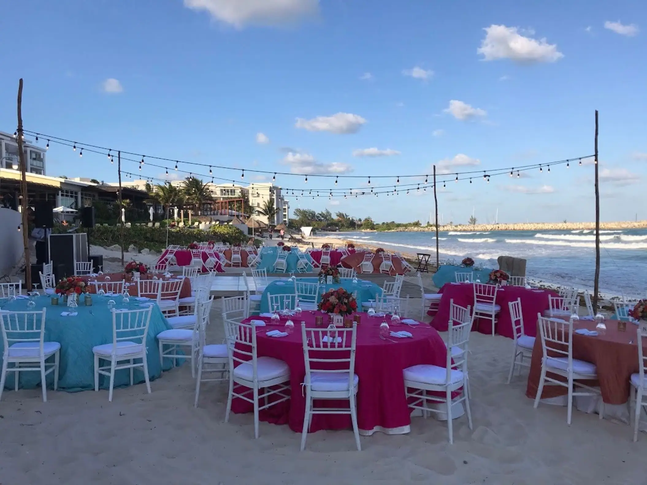 Beachfront wedding reception setup with turquoise and pink linens at Dreams Jade, Riviera Maya